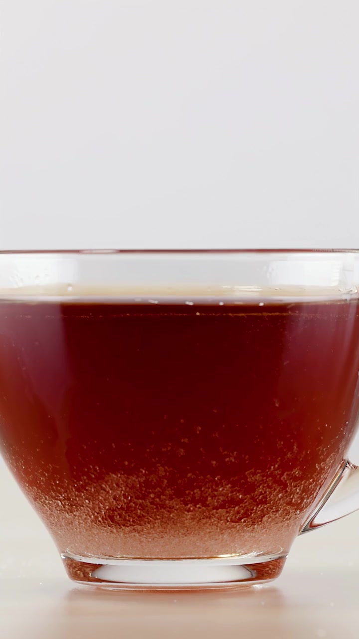 Liquido scuro effervescente che si dissolve in un bicchiere trasparente