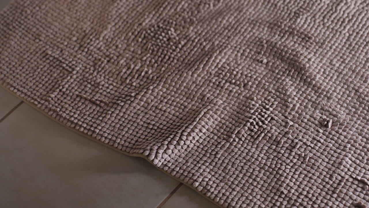 High angle view shows female feet near bathtub, stepping onto beige textured bath mat, toes pressing edge, preparing to enter hot tub, hygiene routine, anti slip comfort, cozy clean bathroom scene