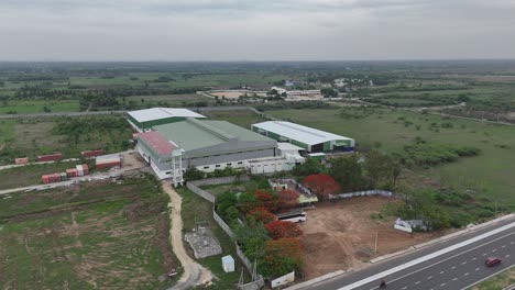 Elevated-footage-of-the-highway-with-a-backdrop-of-distant-city-skyline-near-factory