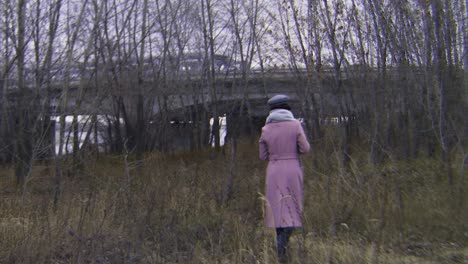 woman walking under a bridge in autumnal forest