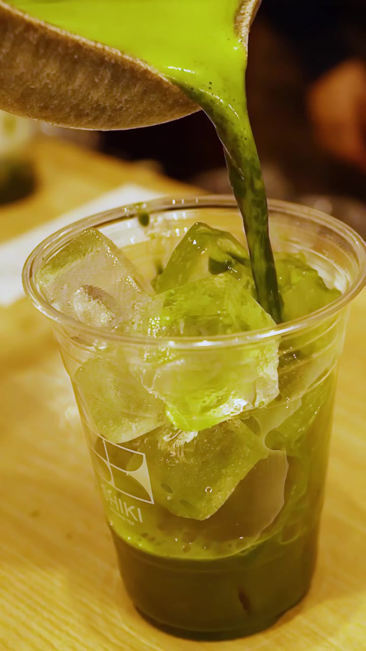 Versando tè verde Matcha fresco su ghiaccio in un bicchiere di plastica