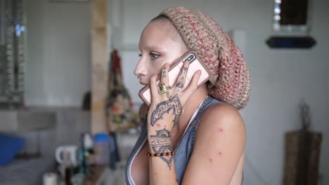 una chica joven, genial, tatuada, de aspecto alternativo con un gorro está teniendo una intensa discusión por teléfono con alguien