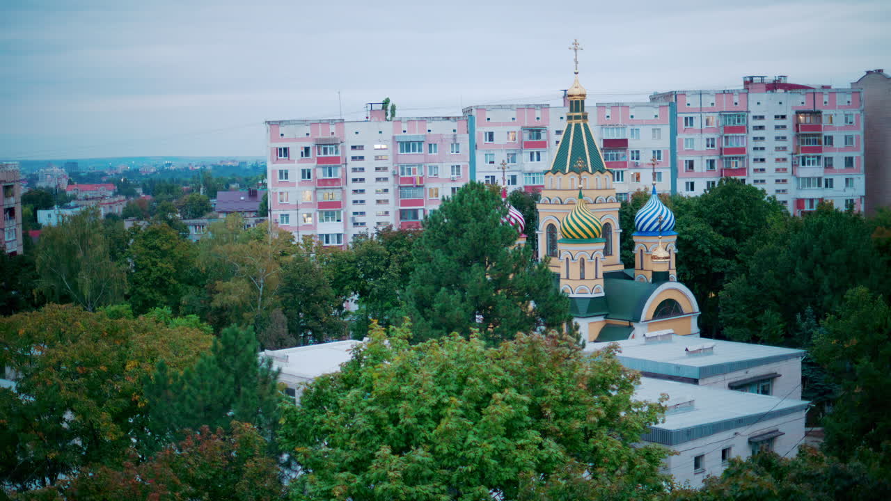 Aerial view of a colorful Orthodox church with onion domes, framed by residential apartment blocks and greenery