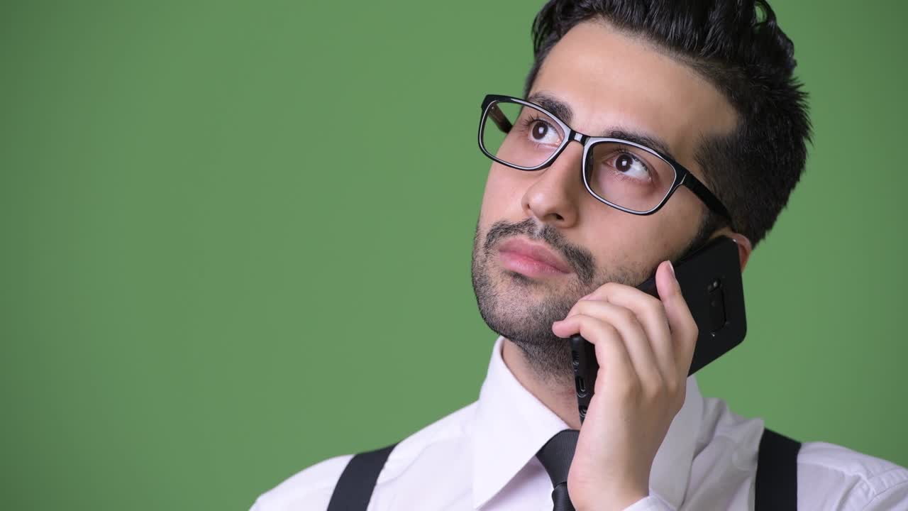 joven empresario persa barbudo y guapo contra un fondo verde