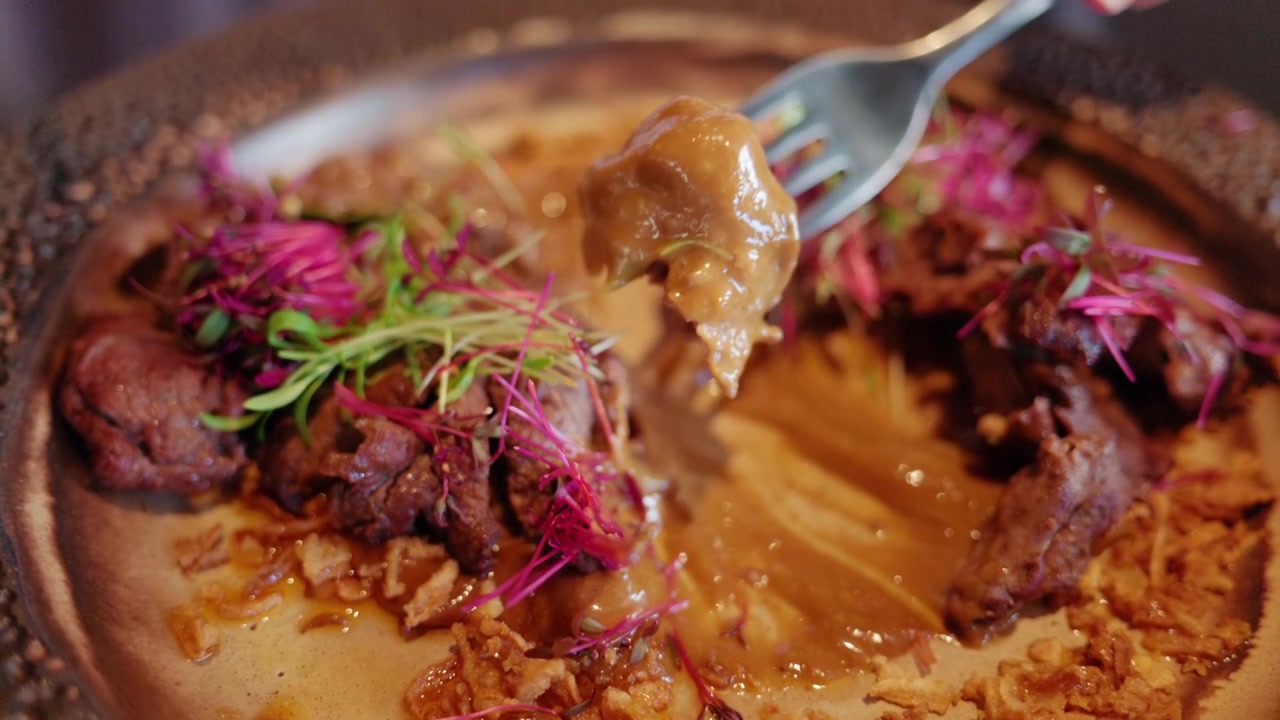 Primer plano de plato gourmet de carne con salsa y microvegetales