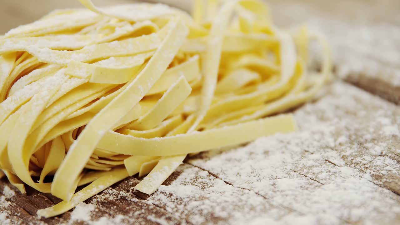 밀가루 가루 를 뿌린 나무 배경 에 있는 tagliatelle 파스타 의 클로즈업