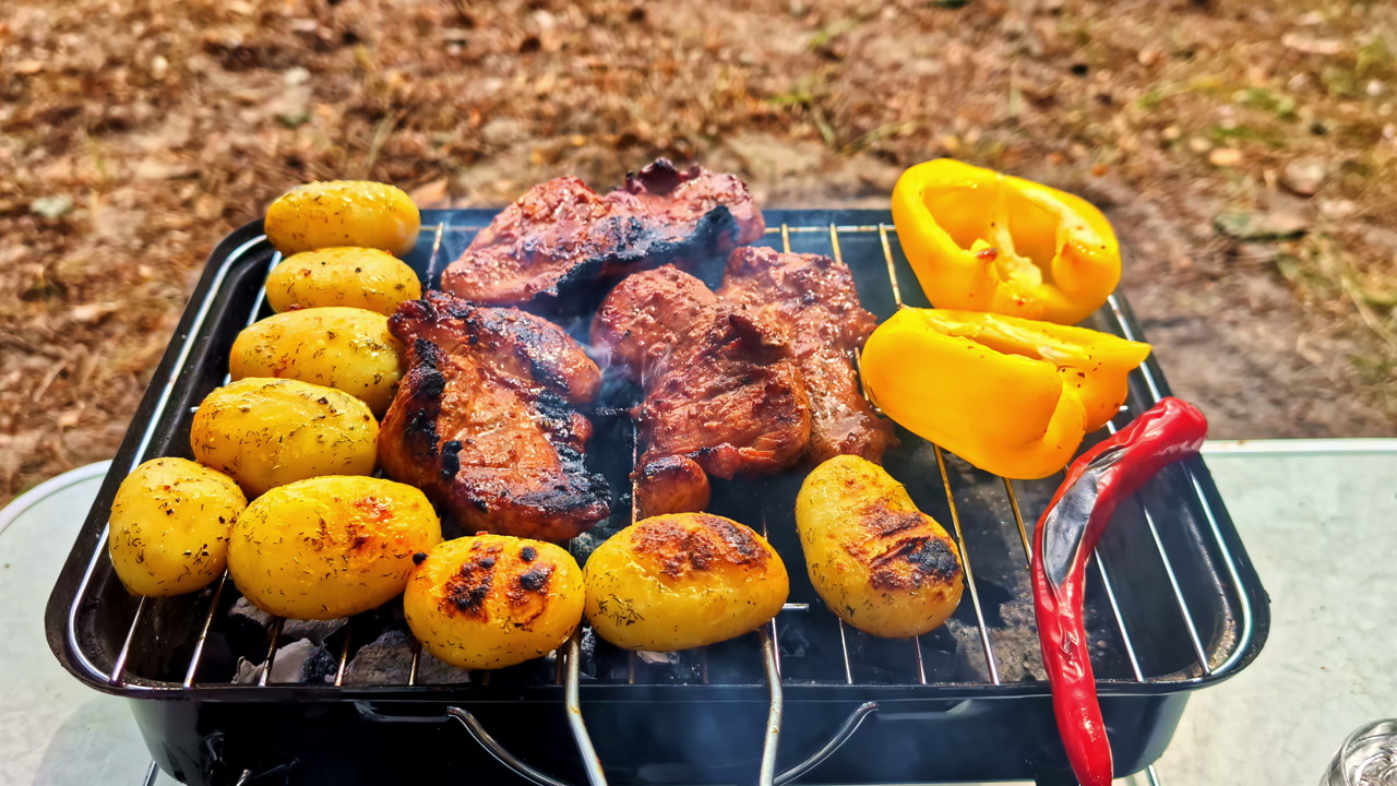 Lakeside Campsite In Engure, Latvia, With Tents Pitched On Grassy Ground And Grill In Foreground Cooking Meat, Potatoes, And Bell Peppers. tilt-up reveal