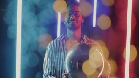 man holding disco ball under neon lights