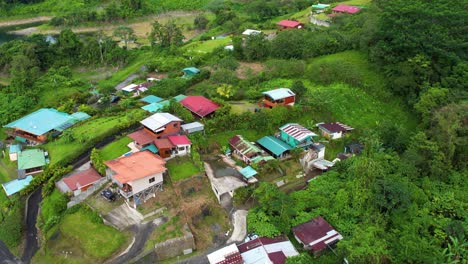 drone flies above small costa rican villagesnestled in the hills near lake arenal. brightly coloured rooftops, winding roads, and scattered homes reflect local life in this peaceful rural landscape