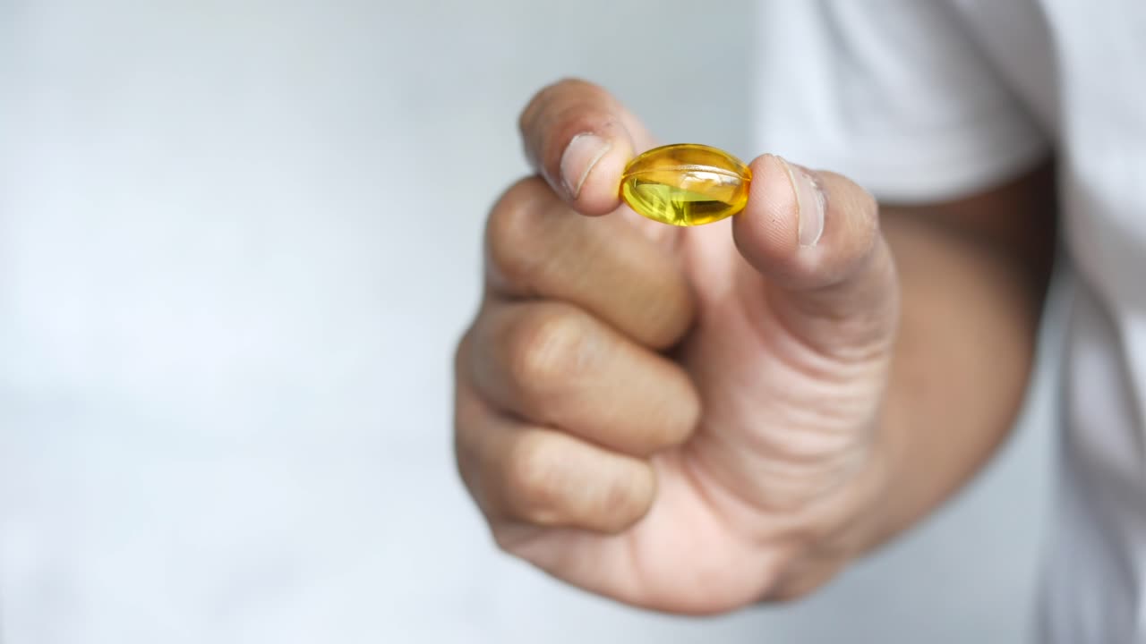 persona que sostiene una cápsula amarilla