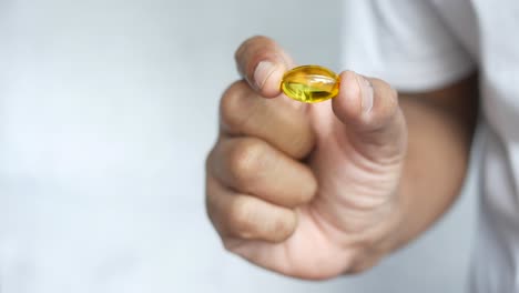 person holding a yellow capsule