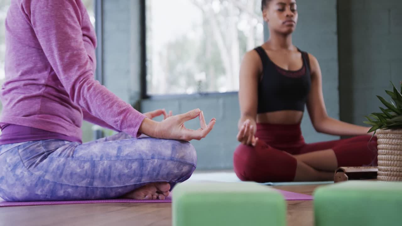 mujeres multirraciales practicando meditación y mudra de paciencia en el estudio de yoga