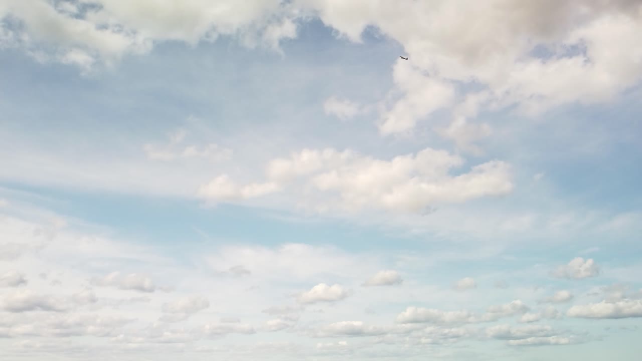 푹신한 구름과 함께 낮 시간 하늘을 날아가는 비행기의 극단적인 와이드 샷