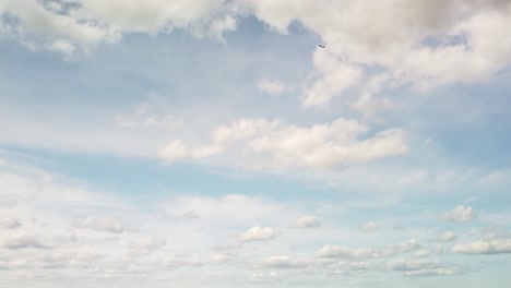 Extreme-wide-shot-of-an-airplane-flying-through-a-day-time-sky-with-fluffy-clouds