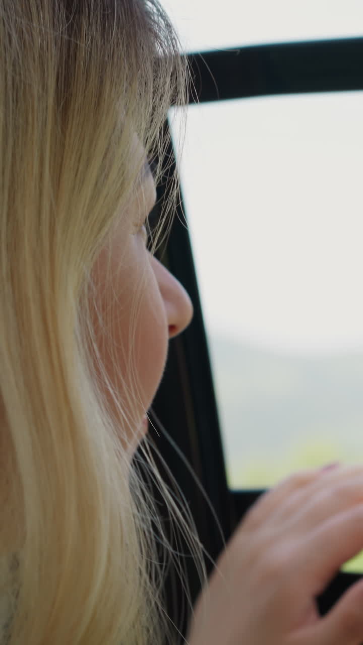 Joyful blonde lady sticks hand out of contemporary poma lift cabin enjoying comfortable riding at highland resort close view slow motion