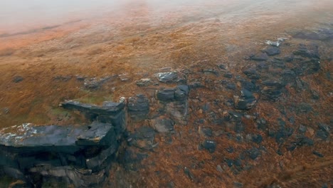 aerial footage of clouds moving slowly over the hills, pennines on a foggy morning, golden hills and beautiful rocky cliffs and moorlands