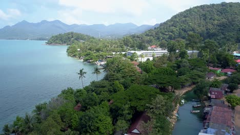 aerial of a tropical beach front by the beach on an island with mountains in the background