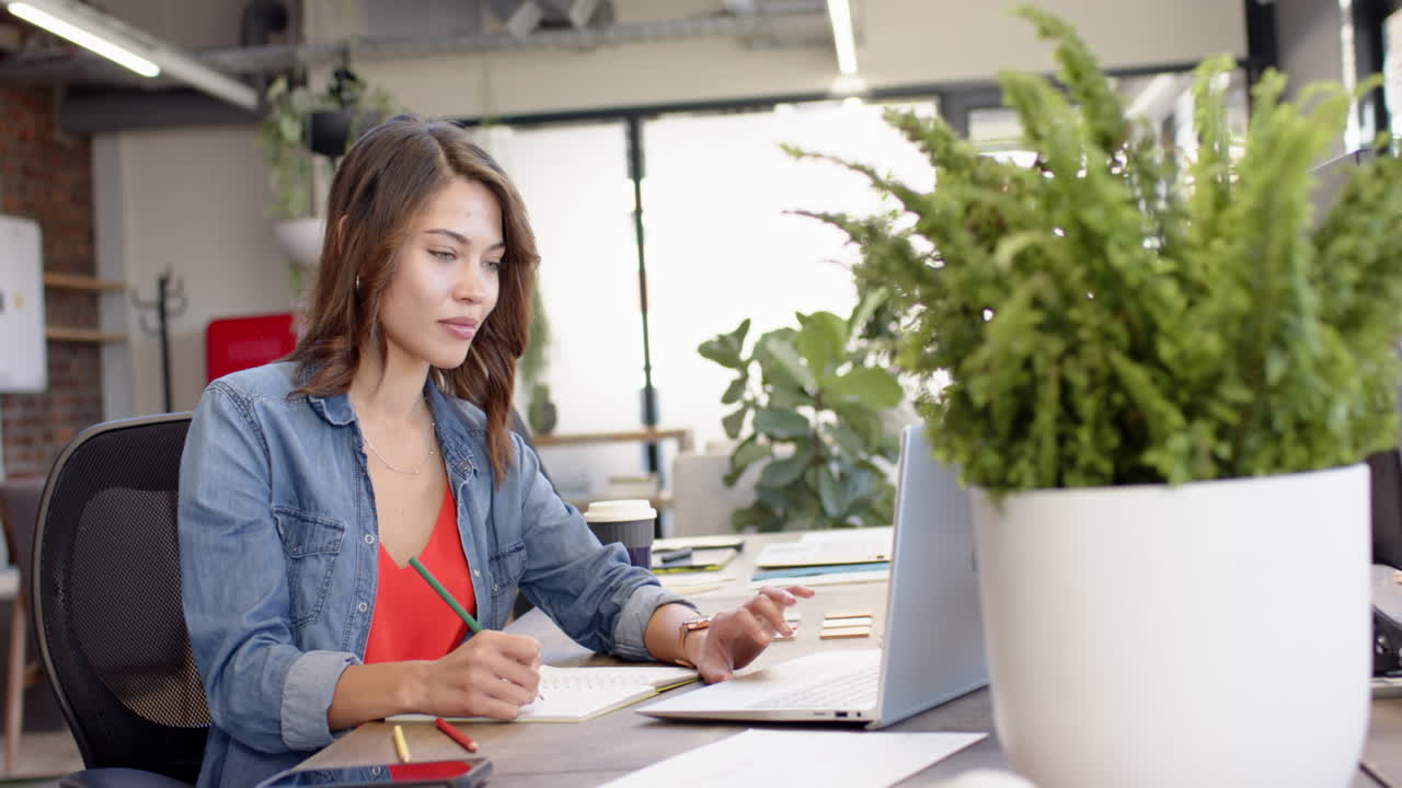 Donna che lavora in ufficio, usa un laptop e prende appunti, concentrandosi sul lavoro
