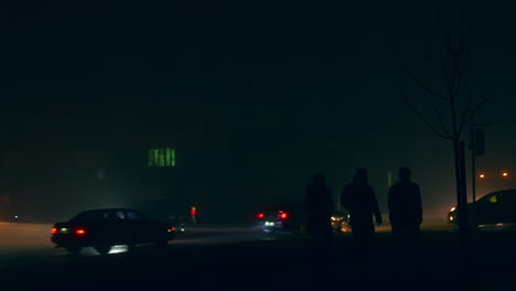 people walking in foggy night city street