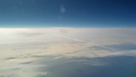 vista increíble desde la cabina de un avión que vuela alto por encima de las nubes dejando un largo rastro de aire de vapor de condensación blanco en el cielo azul