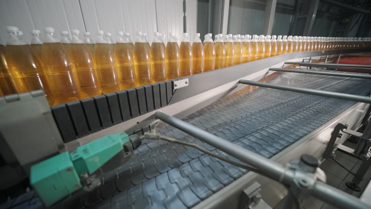 Esteira transportadora com garrafas para suco ou água em uma moderna fábrica de bebidas. Produção moderna de água gaseificada doce.