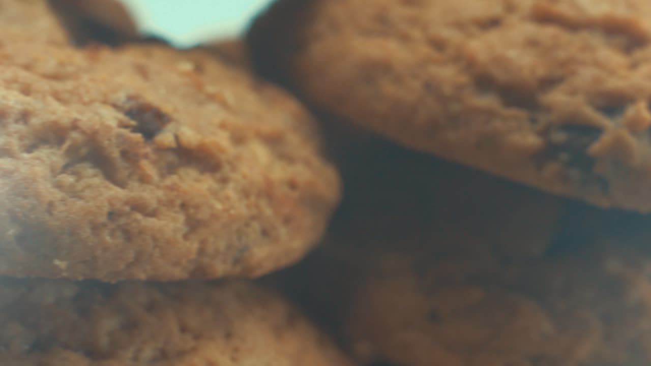 A macro close up shot of a white plate full of crispy chocolate chip cookies, on a 360 rotating stand, studio lighting, slow motion, 4K video