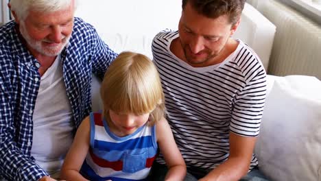 Boy-sitting-with-his-father-and-grandfather-in-living-room