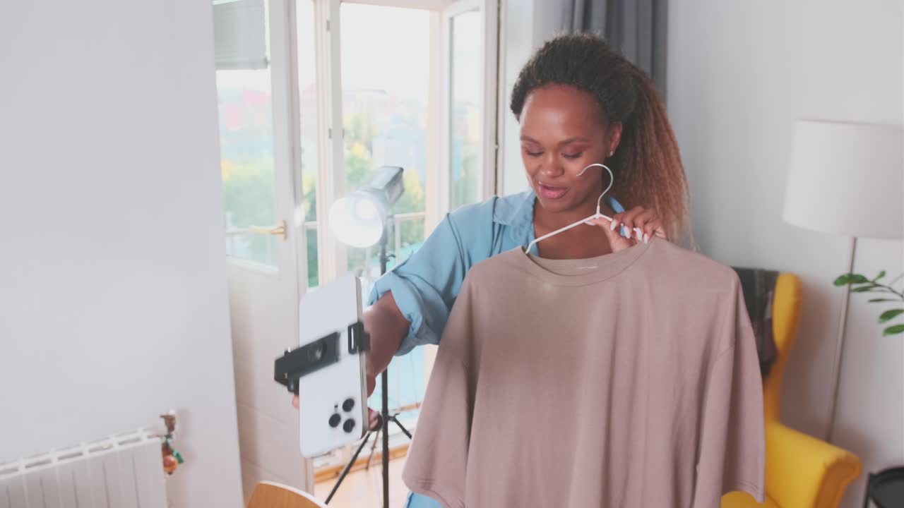 Young cheerful african american woman blogger records video on mobile phone