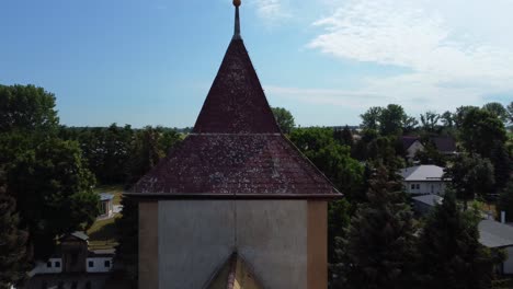 Vista-Aérea-Más-Tranquila-Muy-Cerca-Pasando-Imágenes-De-Aviones-No-Tripulados-De-Vuelo-De-Una-Aguja-De-La-Torre-De-La-Iglesia-En-El-Pueblo-Rural-Hainichen-En-Europa-Sajonia-Anhalt,-Verano-2022-4k-Vista-Cinematográfica-Desde-Arriba-Por-Philipp-Marnitz