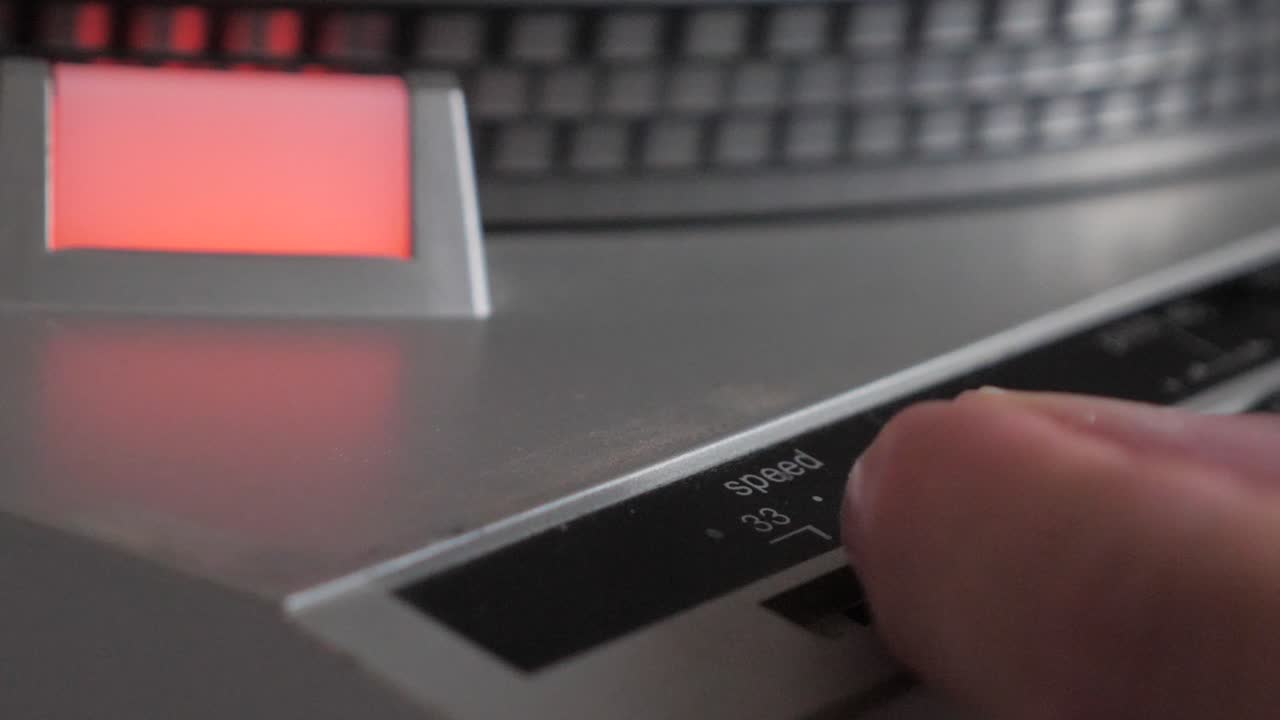 рука, переключающая скорость вращения виниловой пластинки на старинном проигрывателе