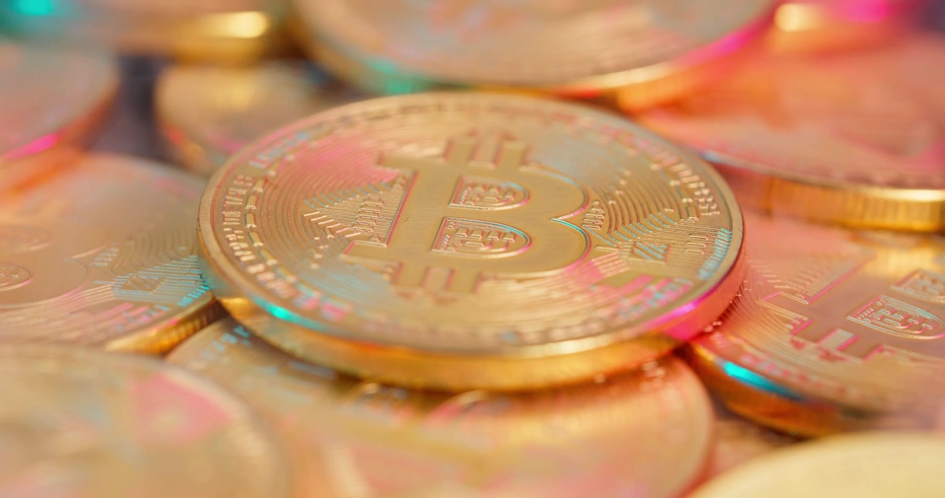 Primo piano di una moneta Bitcoin dorata con riflessi colorati