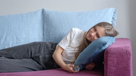 Girl-laying-on-the-sofa-and-watching-tv,-with-remote-in-hand,-in-Slow-Motion