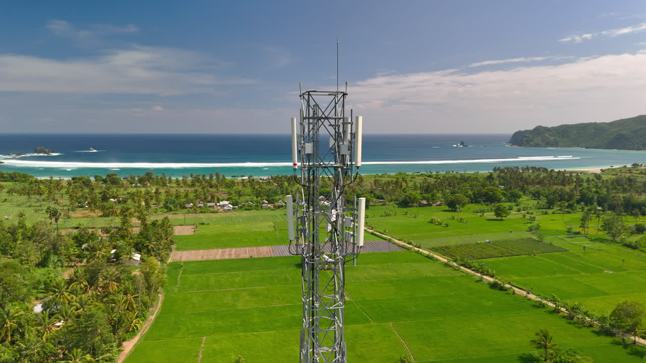 torre de celdas que se eleva sobre campos verdes con la playa de pantai lansing lombok y el océano en el fondo