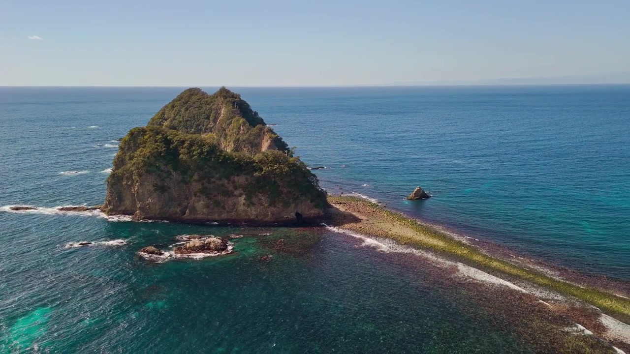 Splendida ripresa con drone che segue un'isola ripida e rocciosa circondata da acque blu intenso e verde smeraldo lungo la suggestiva costa di Dogashima.