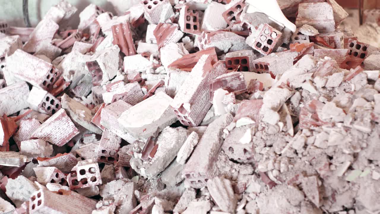 케이블이 매달려있는 부서진 벽을 드러내기 위해 벽돌 어리에서 카메라를 기울입니다.