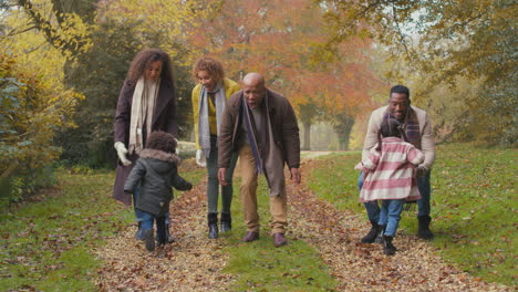 Familia-Sonriente-De-Varias-Generaciones-Divirtiéndose-Con-Niños-Caminando-Juntos-Por-El-Campo-Otoñal