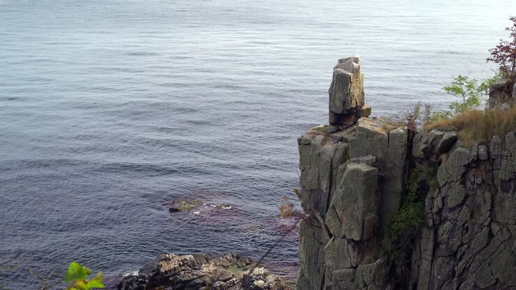 Teleoptagelse af Helligdomsklipperne mole på Bornholm, Danmark, nær kunstmuseet på en solrig sommerdag, med grønne planter der indrammer udsigten over havet.