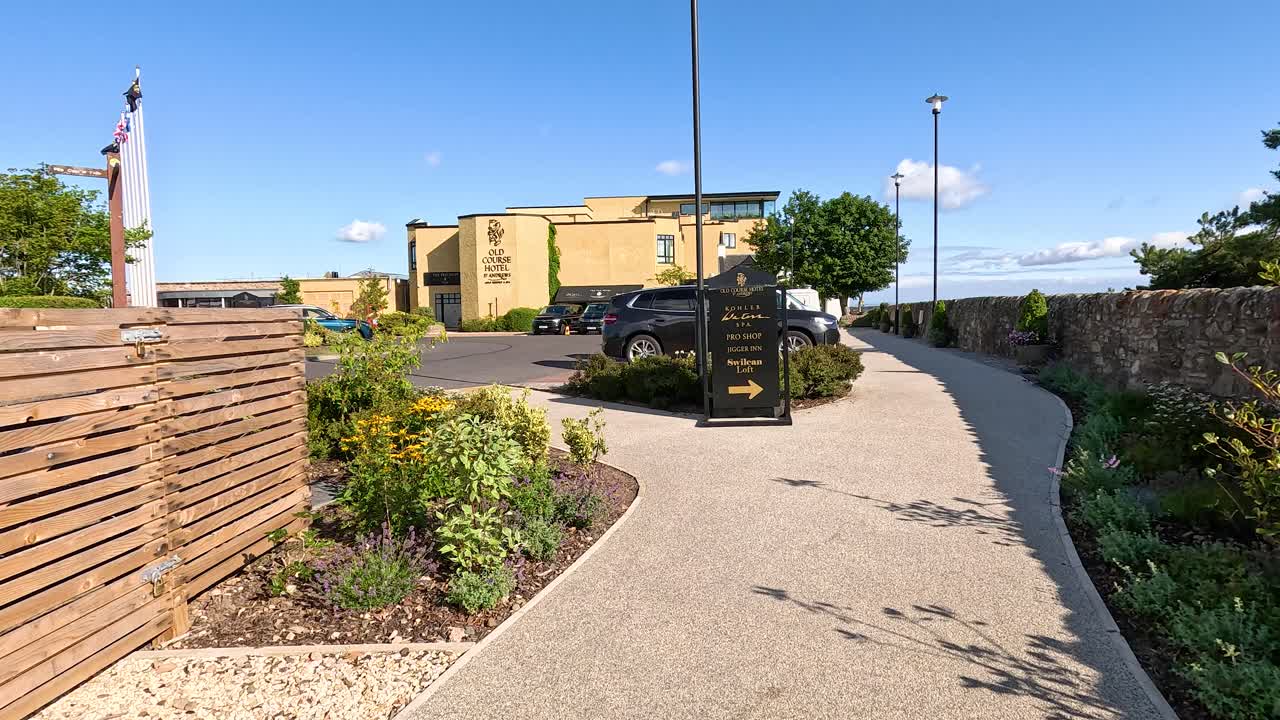 Camera glides along landscaped path toward upscale golf resort hotel under bright summer sky