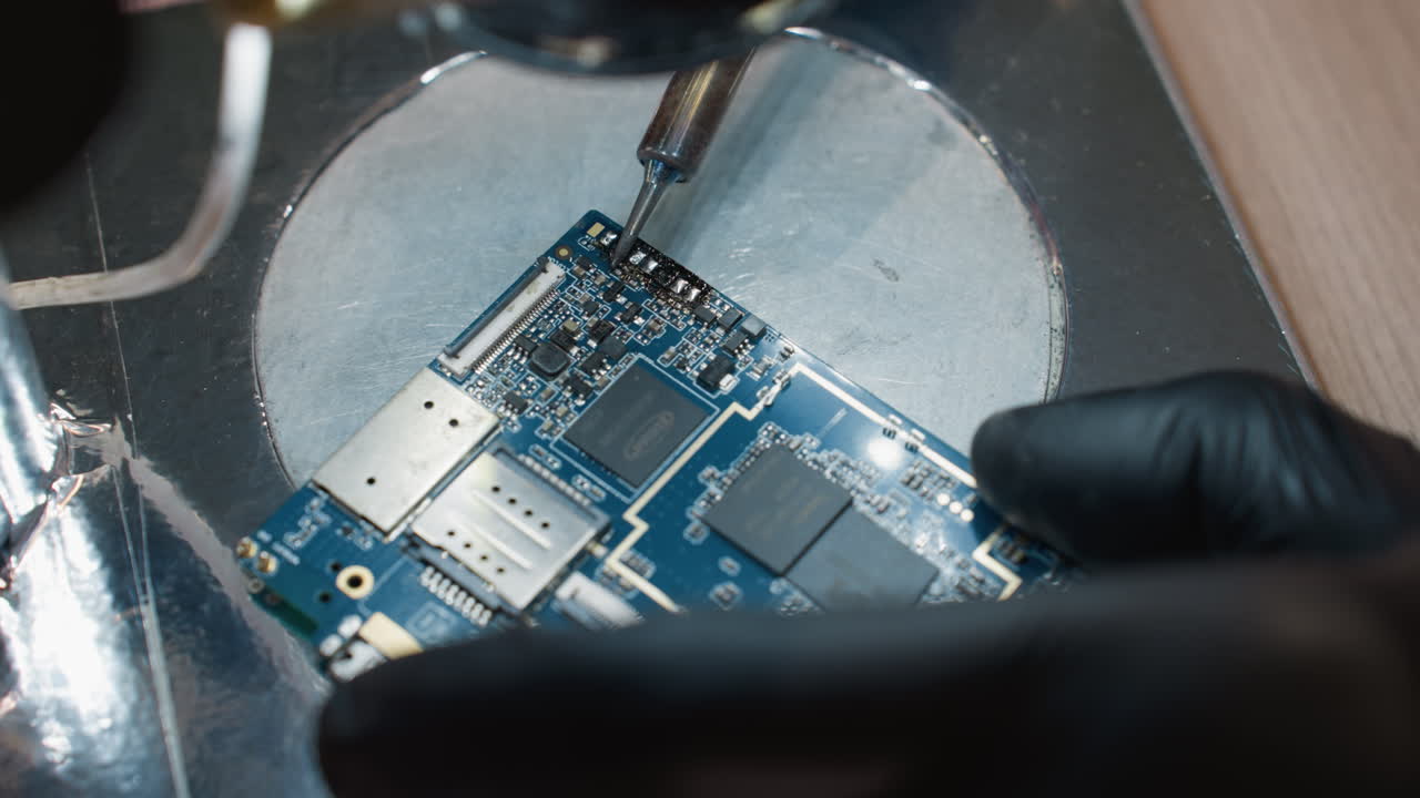 A close-up view of a technician meticulously soldering a printed circuit board with a soldering iron with the environment lit up