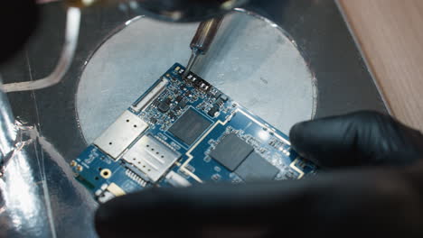 a close-up view of a technician meticulously soldering a printed circuit board with a soldering iron with the environment lit up