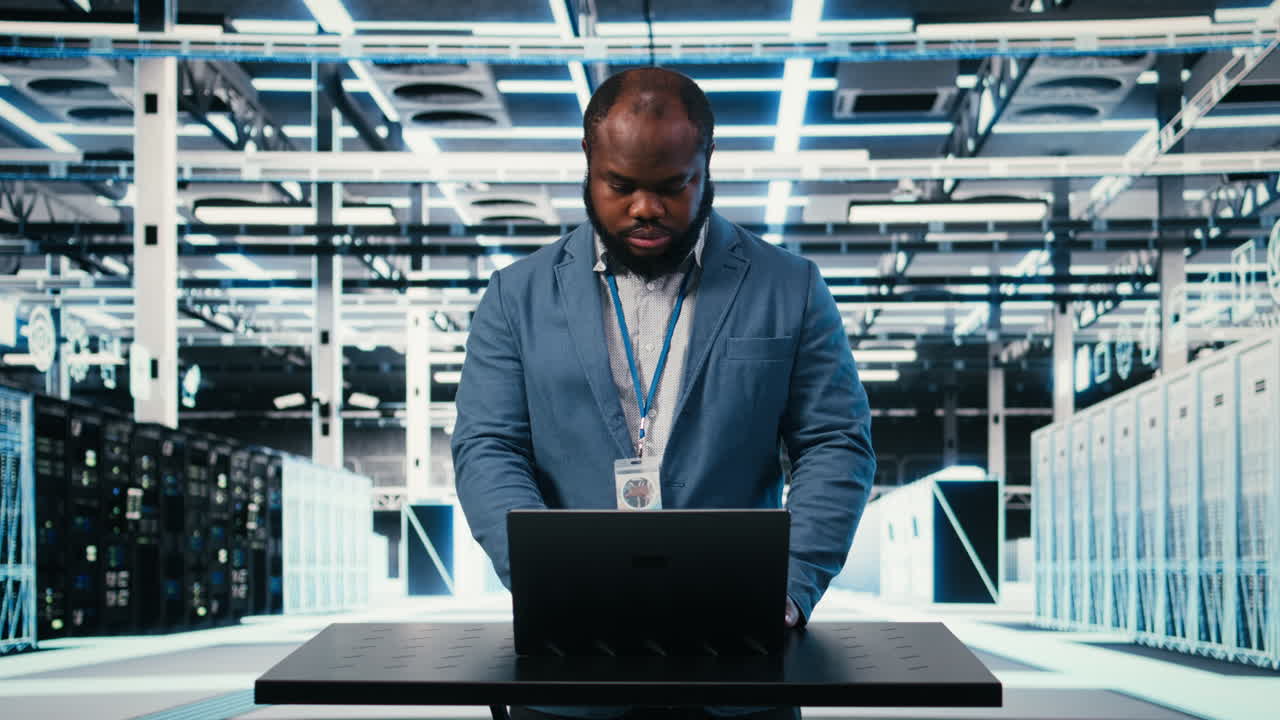 IT Professional Working on Laptop in Futuristic Data Center