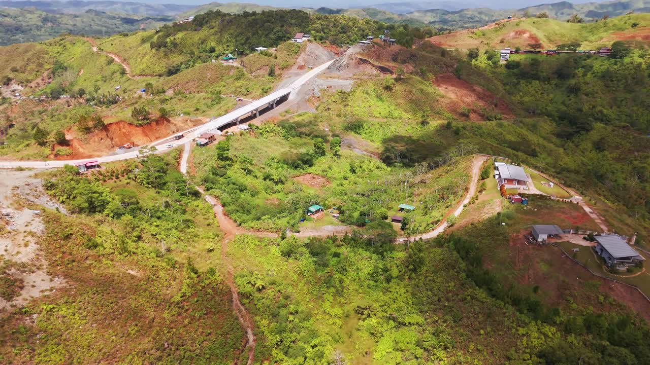 Drone view of a massive concrete bridge construction project cutting through the lush mountains of Davao. Ongoing rural infrastructure development connecting remote communities in the Philippines
