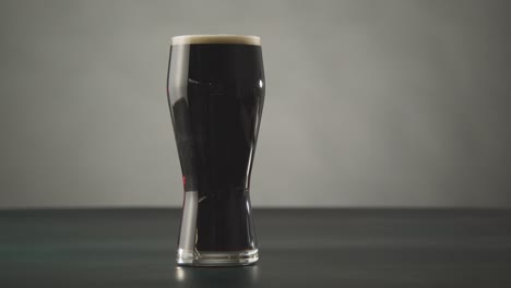 pinta de cerveza negra irlandesa en vidrio contra el fondo del estudio para celebrar el día 1 de san patricio