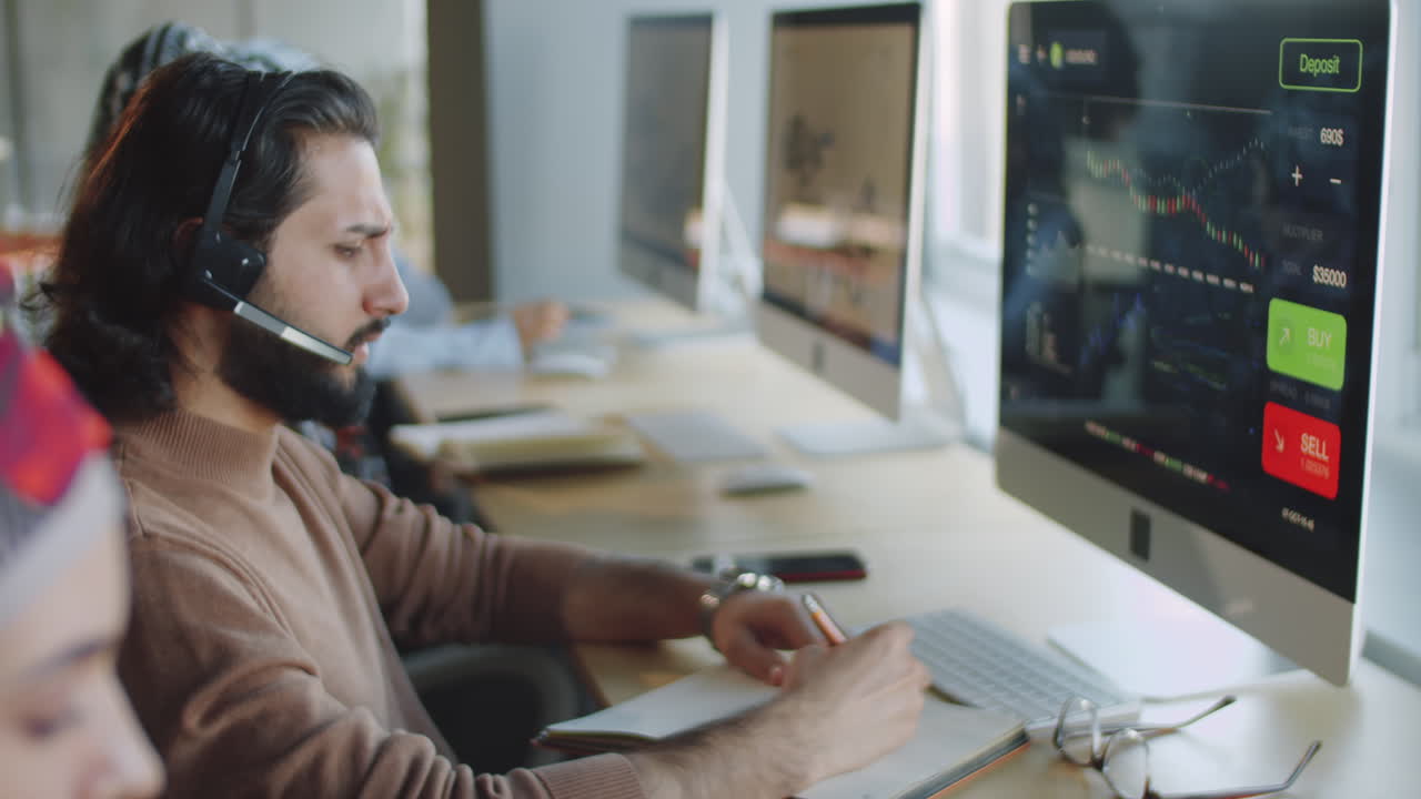 hombre de negocios de oriente medio con auriculares usando computadora y tomando notas