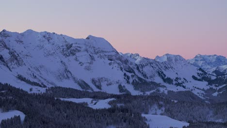 Witness-the-breathtaking-sunrise-over-a-snow-capped-mountain-range-silhouette-from-this-stunning-drone-viewpoint