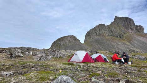 dynamic timelapse showing two tourists setting up their campsite on a black sand beach beneath towering mountains in iceland, coastal landscapes.