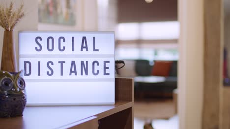Woman walks in and Switches on Decorative Lightbox Written Social Distance in Comfy and Cozy Home