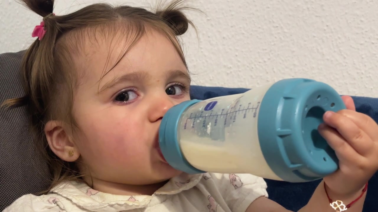 Primo piano di una bambina che beve latte dal biberon, alimentazione infantile e cura della prima infanzia. Primo piano