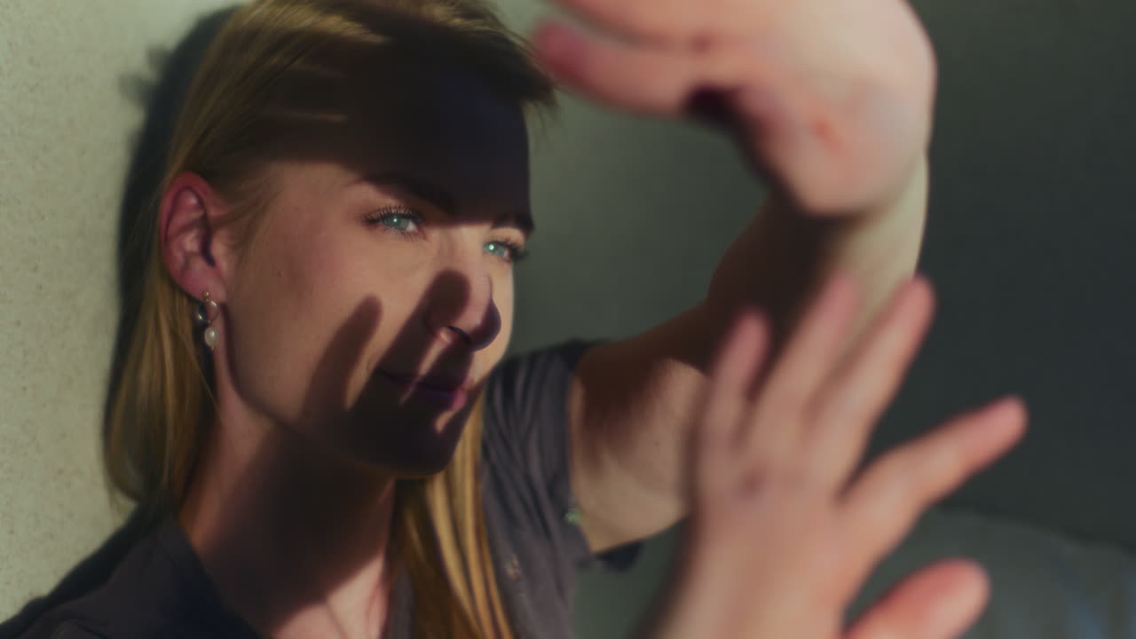 사려 깊고 꿈꾸는 여성이 손으로 빛을 잡습니다.