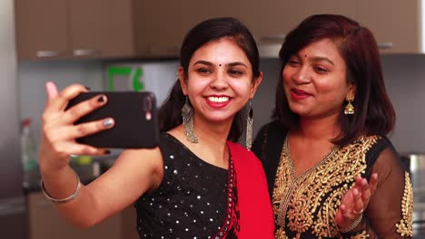 dos hermosas mujeres indias hablando con la familia en línea llamada de video usando ropa tradicional étnica para diwali u otra celebración de festival